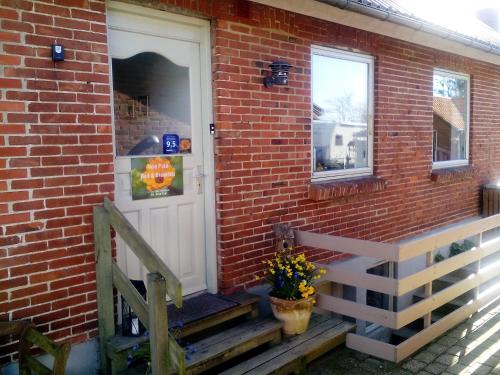 a brick house with a white door and stairs at B&B Villa Filsø in Tim