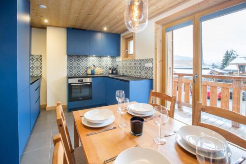 une cuisine avec une table en bois, des assiettes et des verres dans l'établissement 2 bedroom haven in enviable Morzine location, à Morzine