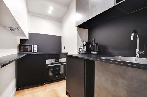 - une cuisine noire avec évier et four micro-ondes dans l'établissement Les Halles - Grands Boulevards Cozy 1BR - 4P, à Paris
