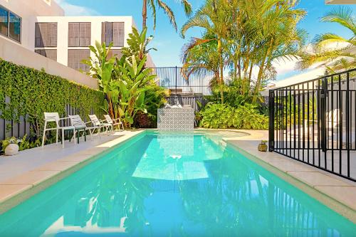 a swimming pool in a yard with chairs and a building at Fletcher Lane Boutique Stay Byron Central in Byron Bay
