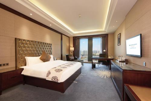 a hotel room with a bed and a flat screen tv at Wyndham Grand Plaza Royale Chenzhou in Chenzhou