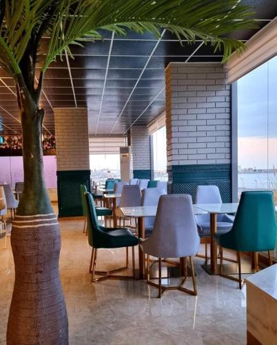 a restaurant with tables and chairs and a tree at Amwaj hotel Mirbat in Salalah