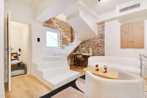 Il comprend un salon doté d'un mobilier blanc et d'un mur en briques. dans l'établissement Les Halles - Grands Boulevards Renovated 3BR - 8P, à Paris