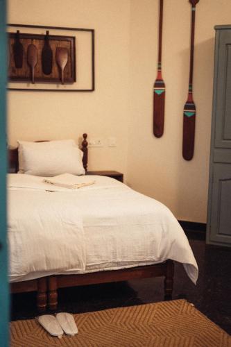 a bedroom with a white bed with utensils on the wall at Paddle Cult Surf & Yoga in Varkala