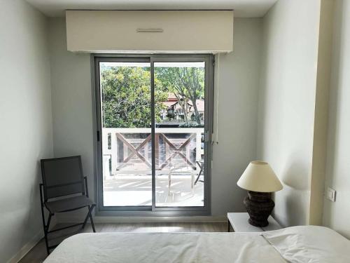 une chambre avec un lit et une fenêtre avec une chaise dans l'établissement Résidence Clos St Arnaud - Arcachon – Charmant appartement à 300 m de la plage, dans le quartier Ville de Printemps MAE-7074, à Arcachon