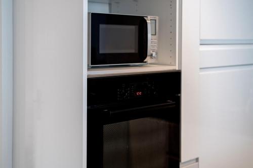 Un four micro-ondes est installé au-dessus d'un four noir. dans l'établissement Cros de Cagnes 2 pièces Rev001, à Cagnes-sur-Mer