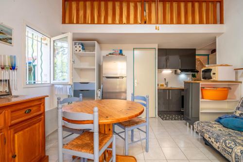 une cuisine avec une table et des chaises dans une pièce dans l'établissement Mini Villa jumelée Hameau du Soleil, à Vendres