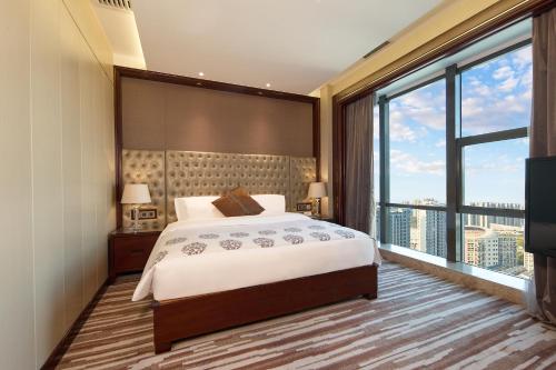 a bedroom with a large bed and a large window at Wyndham Grand Plaza Royale Chenzhou in Chenzhou