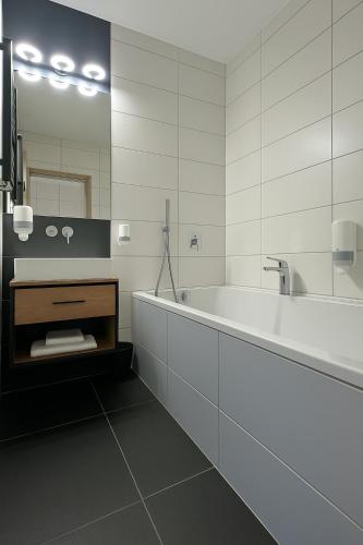 a white bathroom with a tub and a mirror at Leśne Ustronie in Lubiszewo