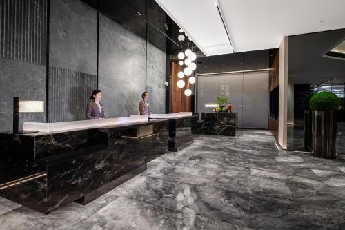 two people standing at a long desk in a lobby at Intercity Hotel Shanghai City Center - Free Mini Bar in Shanghai