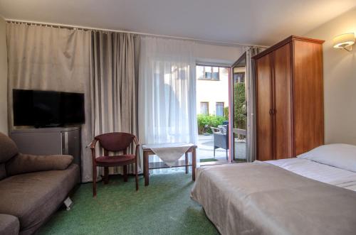 a hotel room with a bed and a chair and a table at Willa Koron a Mielno in Mielno