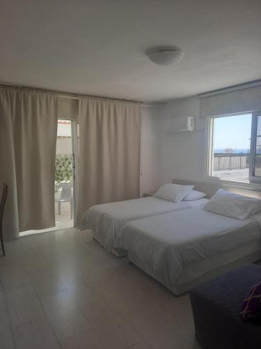 a bedroom with two beds and a large window at Myriama Apartments in Ayia Napa