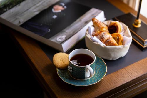 a cup of coffee and a basket of pastries on a table at Dunluce Lodge - Small Luxury Hotels of the World in Portrush