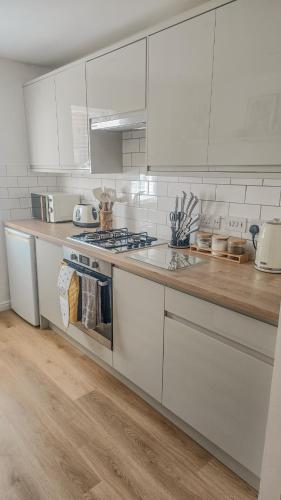 a kitchen with white cabinets and a wooden counter top at Welcome Home in Royston