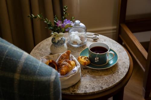 a table with a cup of coffee and pastries on it at Dunluce Lodge - Small Luxury Hotels of the World in Portrush