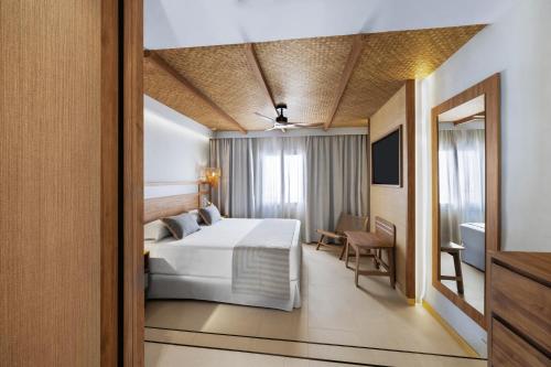 a hotel room with a bed and a television at Hotel Riu Palace La Mola in Playa Migjorn