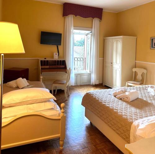 a bedroom with two beds and a desk and a window at Hotel Villa Quiete in Montecassiano