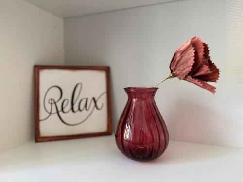 a red vase with a flower in it next to a picture at Ferienhaus Istaby in Sölvesborg