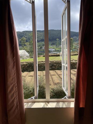 an open window with a view of a field at The Vatican Villa in Nuwara Eliya