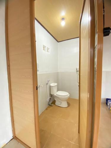 a bathroom with a toilet and a wooden door at Cepogo Cabin Mangli Cabin Keluarga & Syariah in Prampelan