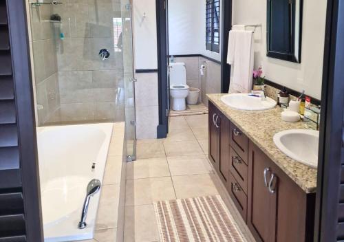a bathroom with a tub and two sinks and a shower at Bona Bali 14, Zimbali Estate by Euphoric Leisure in Ballito