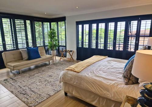 a bedroom with a bed and a couch and windows at Bona Bali 14, Zimbali Estate by Euphoric Leisure in Ballito