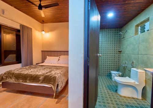 a bedroom with a bed and a bathroom with a toilet at Pine Malhar Pool Stay by VOYE HOMES in Attappādi
