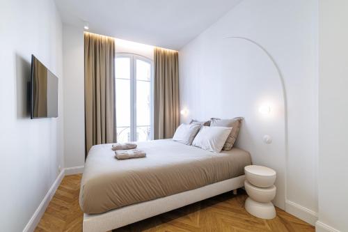 une chambre blanche avec un lit et une fenêtre dans l'établissement Maison Galbani Architect-designed apartment, à Nice