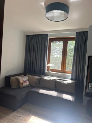 a living room with a couch in front of a window at Świat Jezior in Mikołajki