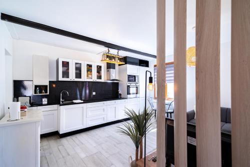 une cuisine avec des placards blancs et une salle à manger dans l'établissement La Petite Parenthèse Jardin, Parking & Proche Gare, à Trappes