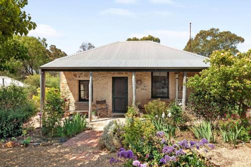 a small brick house with a porch and flowers at Idyllic, peaceful and historical cottage minutes from Bendigo's CBD in Golden Square