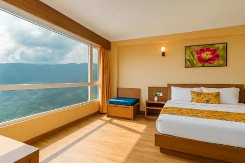 a hotel room with a bed and a large window at Summit Namnang Courtyard & Spa Near Mg Marg in Gangtok
