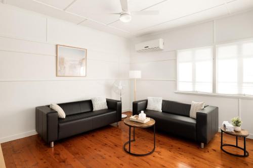 a living room with two black couches and a table at Smart Suites Self Check-In Cottage - Carina in Brisbane