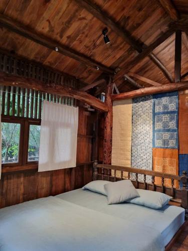 a bed in a room with wooden walls and windows at Yên homestay in Hoi An