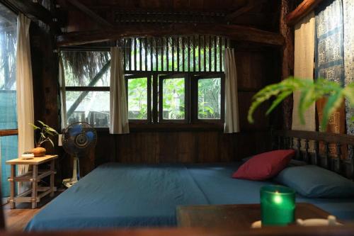 a bedroom with a large blue bed with two windows at Yên homestay in Hoi An