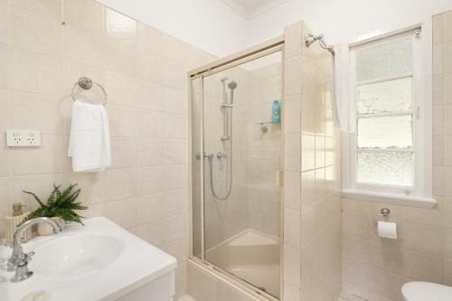 a white bathroom with a shower and a sink at Smart Suites Self Check-In Cottage - Carina in Brisbane