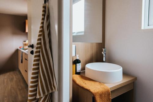 une salle de bain avec un lavabo blanc et une chaise dans l'établissement Camping Liberté Verdon, à Artignosc-sur-Verdon