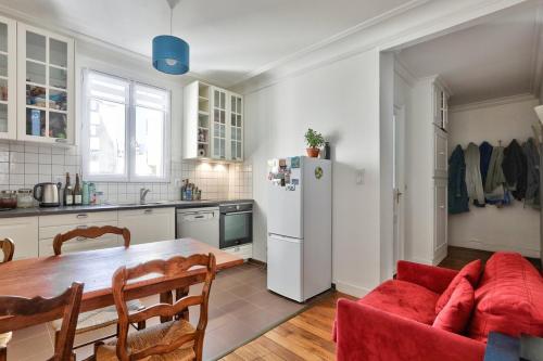 une cuisine avec une table et un réfrigérateur blanc dans l'établissement Lumineux & spacieux - Paris 14, à Paris