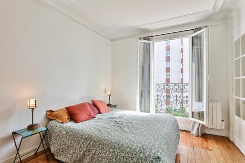 une chambre avec un lit et une grande fenêtre dans l'établissement Lumineux & spacieux - Paris 14, à Paris