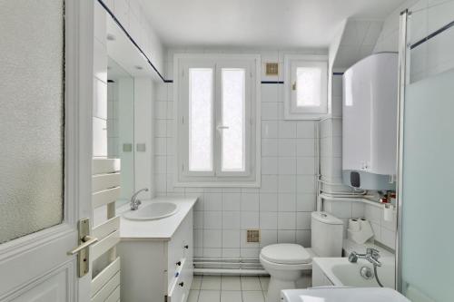 une salle de bain blanche avec un lavabo et des toilettes dans l'établissement Lumineux & spacieux - Paris 14, à Paris