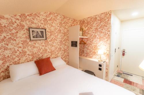 a bedroom with a white bed and floral wallpaper at Résidence du Théâtre in Bordeaux