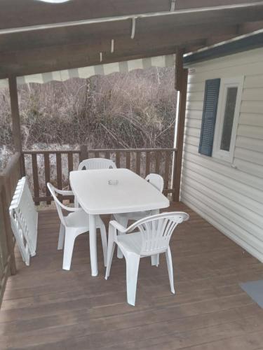 une table et des chaises blanches sur une terrasse dans l'établissement Mobile Home sleeps 4, à Monsec