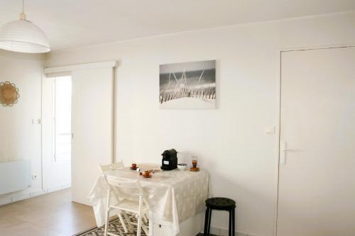une salle à manger blanche avec une table et des chaises blanches dans l'établissement Studio cozy face à la gare, centre ville, wifi, à La Rochelle