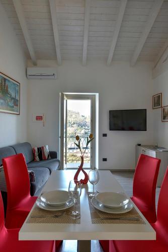 a living room with a table and red chairs at appartamenti i fiori del lago in Laveno