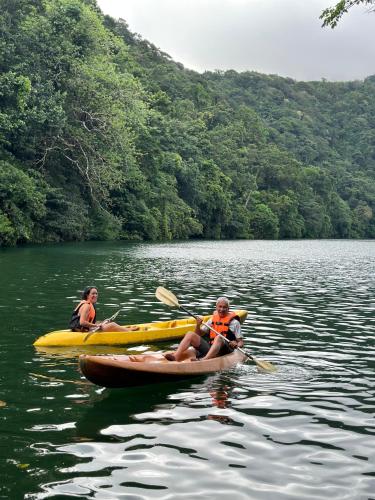 two people in kayaks on a lake with trees at Baia Nest LANAI Glamping in Open Space within Self-Service Villa Near the Beach, Pet Friendly with a Fee in Gubat