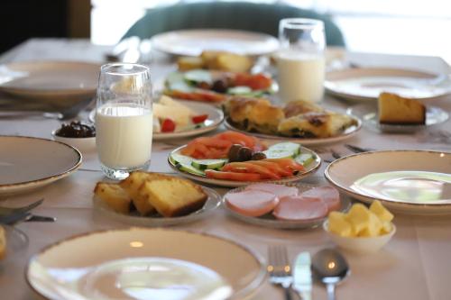 a table with plates of food and glasses of milk at Hotel Kamsi in Berat