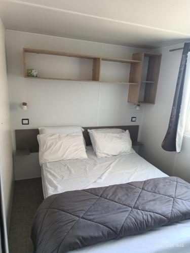 une chambre avec un lit avec des draps blancs et des oreillers dans l'établissement Camping les sablines, à Vendres-Plage