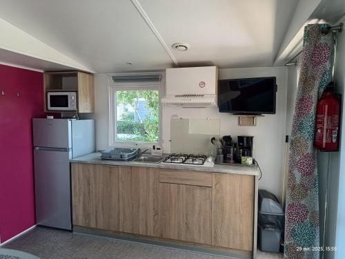 Il comprend une petite cuisine équipée d'un réfrigérateur et d'une cuisinière. dans l'établissement Camping les sablines, à Vendres-Plage