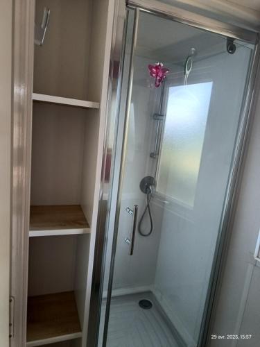 d'une douche avec une porte en verre à l'arc rose. dans l'établissement Camping les sablines, à Vendres-Plage