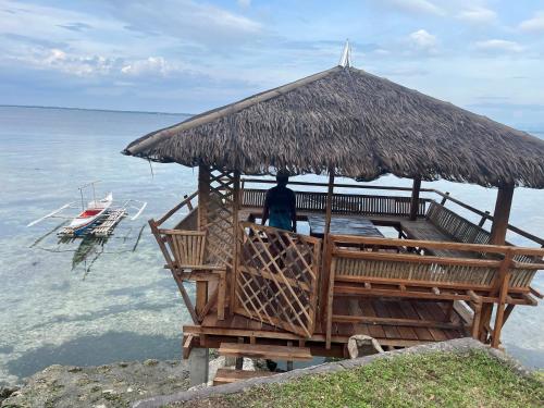 a person sitting on a bench under a straw umbrella at Sondol Guesthouse in Loon